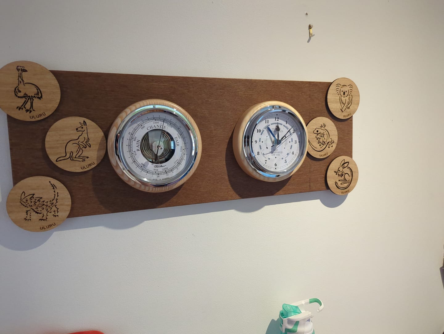 Wall-mounted German barometer and clock set with engraved wooden animal coasters.