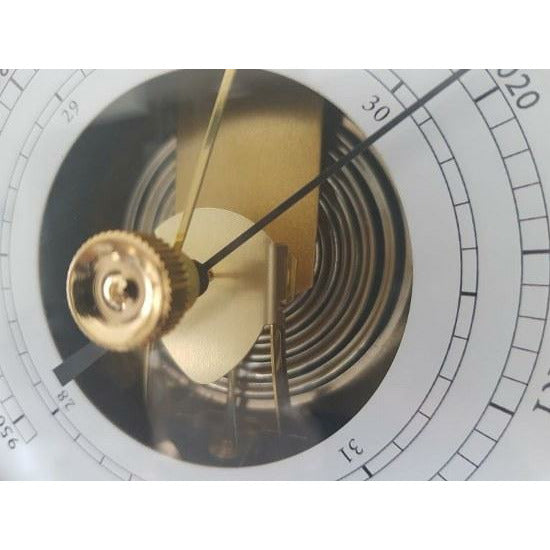Close-up of German barometer dial and mechanism with gold needle and spiral spring.