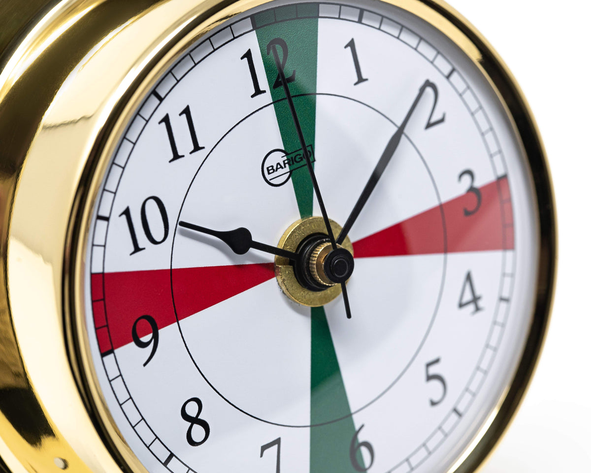 Brass nautical tide clock with red and green dial accents, close-up view
