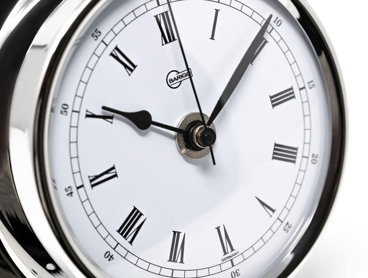 Close-up of classic German-made analog clock with Roman numerals and chrome frame