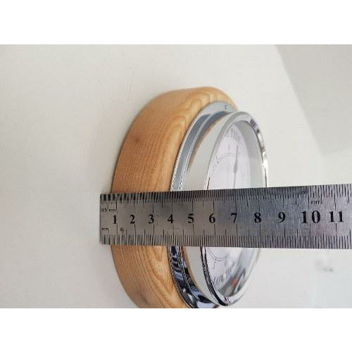 Side view of round barometer with wood frame, chrome trim, and ruler measuring depth