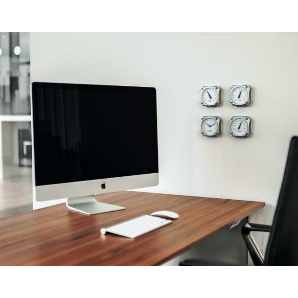 Modern office desk with iMac and four stainless steel weather instruments on wall