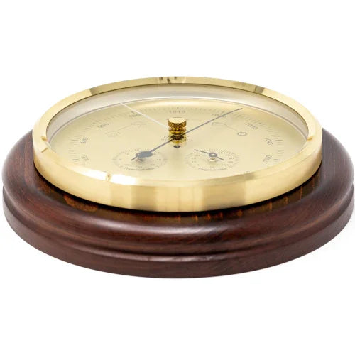Round brass weather station barometer with gold dial on a wooden base