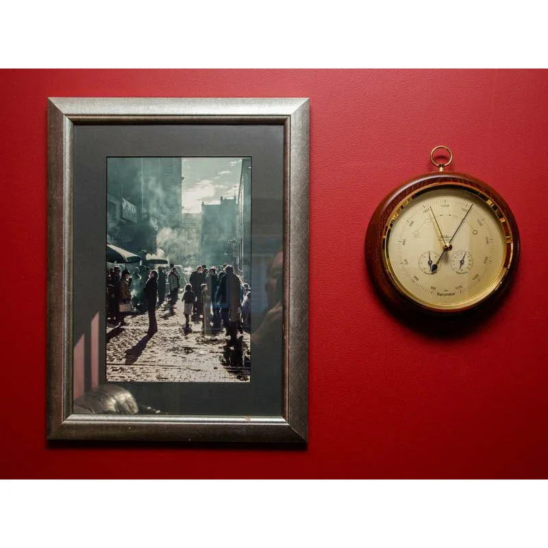 Wall-mounted German barometer and framed art on red wall, home decor setting