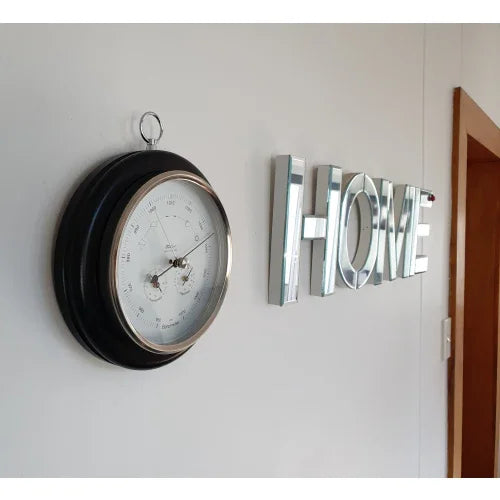 Wall-mounted barometer with white dial near HOME sign in modern hallway
