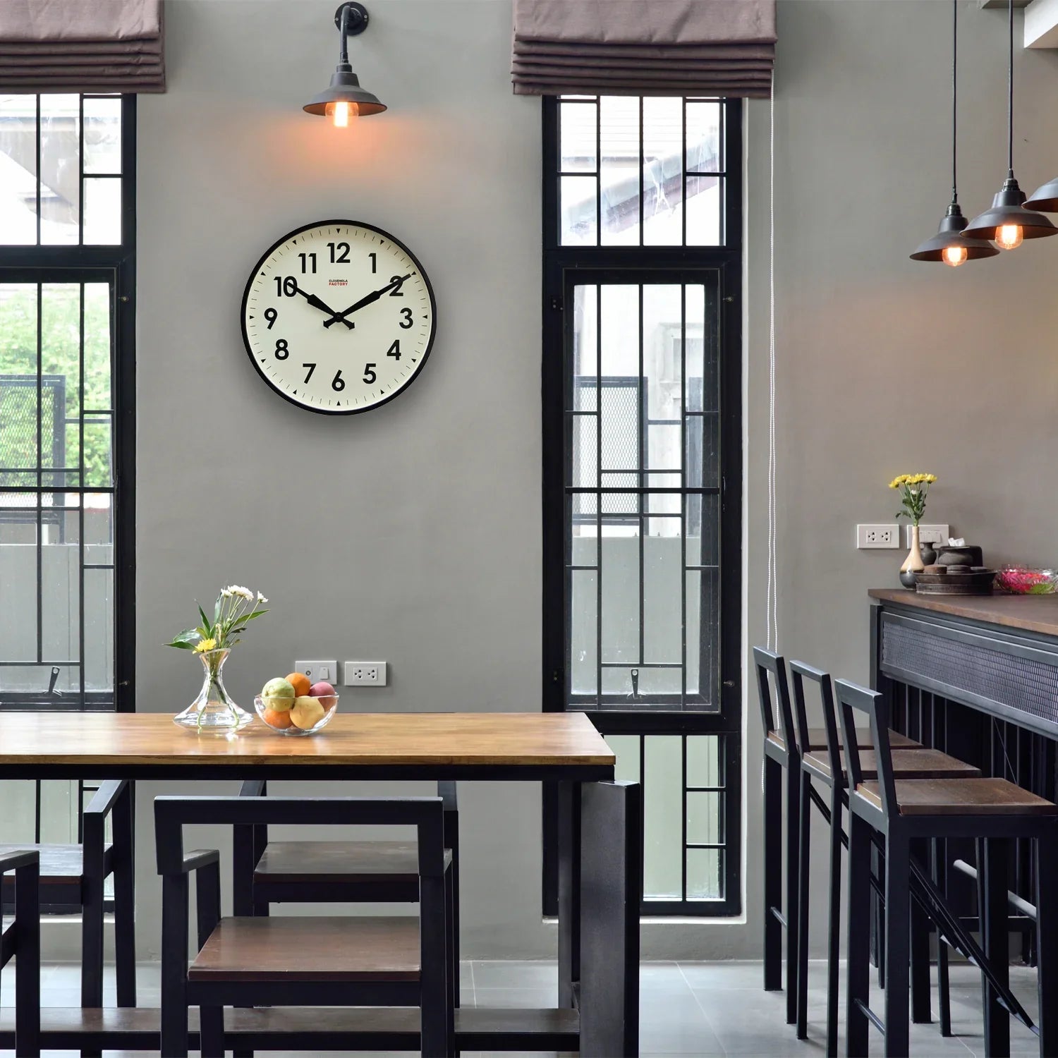 Modern kitchen with large wall clock, wooden dining table and bar stools, natural light